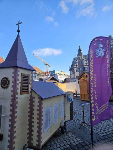 Wagenkirche zwischen den Buden des Weihnachtsmarkts, im Hintergrund das Rathaus